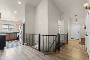 Kitchen with a chandelier, vaulted ceiling, light wood-style flooring, and stainless steel appliances