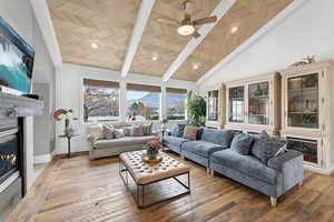 Living room featuring a glass covered fireplace, a mountain view, wood-type flooring, a ceiling fan, and lofted ceiling
