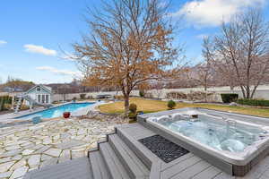 View of pool with patio surround, a water slide, a fenced backyard, an outdoor structure, and a storage structure