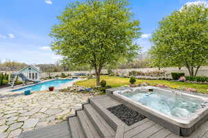 Wooden terrace with a patio area, an outdoor hot tub, a fenced backyard, an outbuilding, and a storage structure