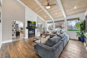 Living area featuring hardwood / wood-style flooring, a tile fireplace, ceiling fan, arched walkways, and lofted ceiling