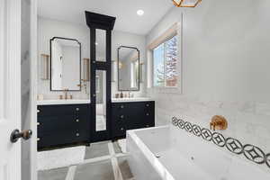 Full bath with two vanities, light tile patterned floors, a whirlpool tub, tile walls, and recessed lighting