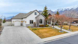 View of front facade featuring stone siding, a mountain view, stucco siding, a gate, and a garage