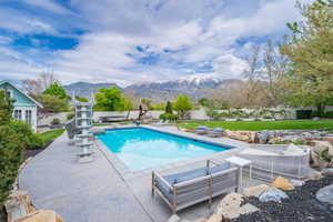 View of pool featuring patio surround, a fenced backyard, a mountain view, and a diving board