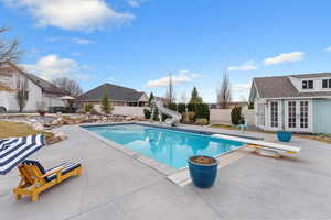 View of swimming pool featuring patio surround, a water slide, an outbuilding, and a fenced backyard
