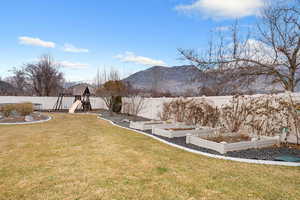 Fenced backyard with a garden, a mountain view, a playground, and a gazebo