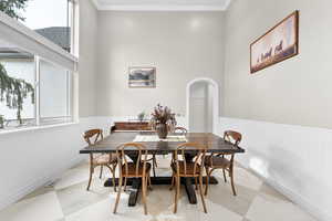 Dining space featuring arched walkways, crown molding, and a high ceiling