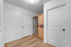 Bedroom featuring a relaxing sauna, light wood-style flooring, a textured ceiling, and a closet