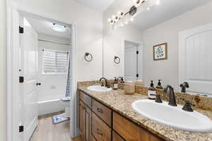 Bathroom featuring double vanity, light wood-style floors, and shower / tub combo