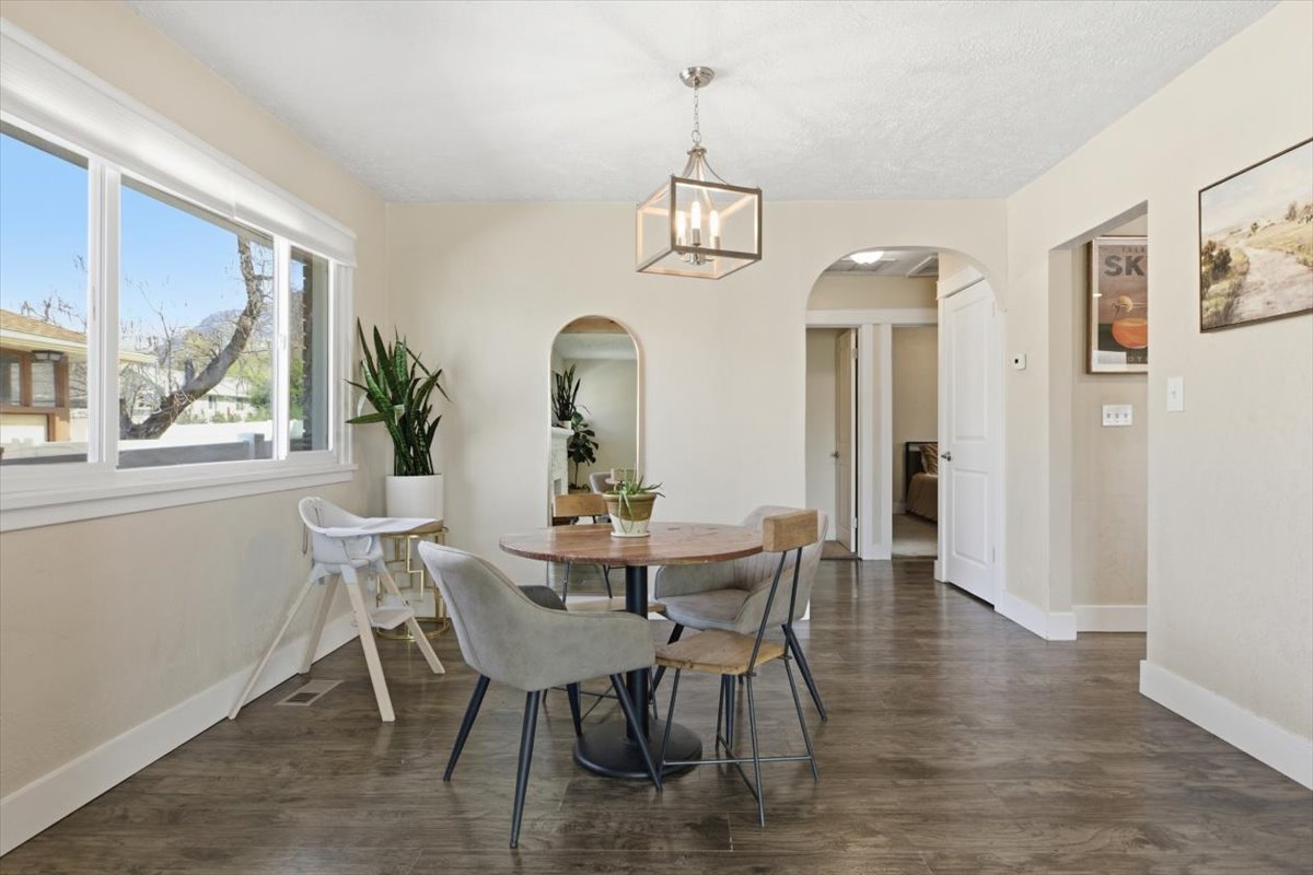 Dining space featuring dark wood finished floors, hanging lights, and arched walkways