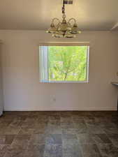 Unfurnished dining area featuring stone finish flooring, suspended lighting, a textured ceiling, and healthy amount of natural light
