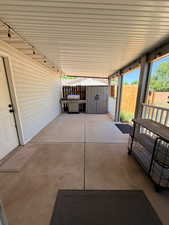 Fenced backyard featuring a patio, grilling area, outdoor dining space, and a storage unit