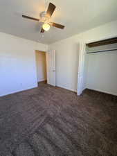 Unfurnished bedroom featuring a textured ceiling, dark carpet, ceiling fan, and a closet