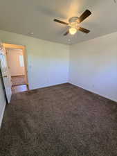 Empty room featuring dark carpet, ceiling fan, and a textured ceiling