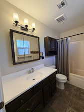 Bathroom featuring vanity, shower / tub combo with curtain, and a textured ceiling