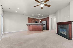 Kitchen featuring open floor plan, a breakfast bar, arched walkways, and a tiled fireplace