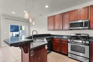 Kitchen featuring stainless steel appliances, a peninsula, light tile patterned flooring, and pendant lighting