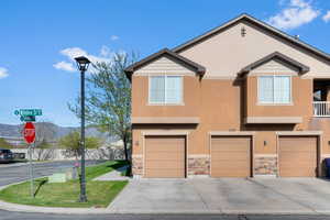 View of front of home featuring stucco siding, an attached garage, and stone siding