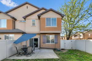 Rear view of property with a gate, a fenced backyard, stucco siding, a patio, and outdoor dining area