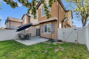 Rear view of property with a gate, a fenced backyard, stucco siding, and a patio area