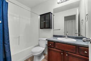 Bathroom with vanity, shower / bath combo, and dark tile patterned floors