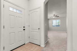 Entrance foyer with light carpet, light tile patterned flooring, ceiling fan, and arched walkways