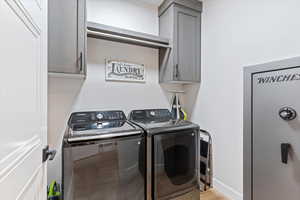 Laundry area with cabinet space, washer and clothes dryer, and light wood-style floors