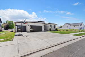 Prairie-style house featuring a garage, concrete driveway, a front lawn, and stone siding