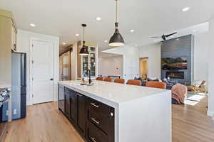Kitchen with a kitchen island with sink, light stone countertops, hanging light fixtures, open floor plan, and stainless steel appliances