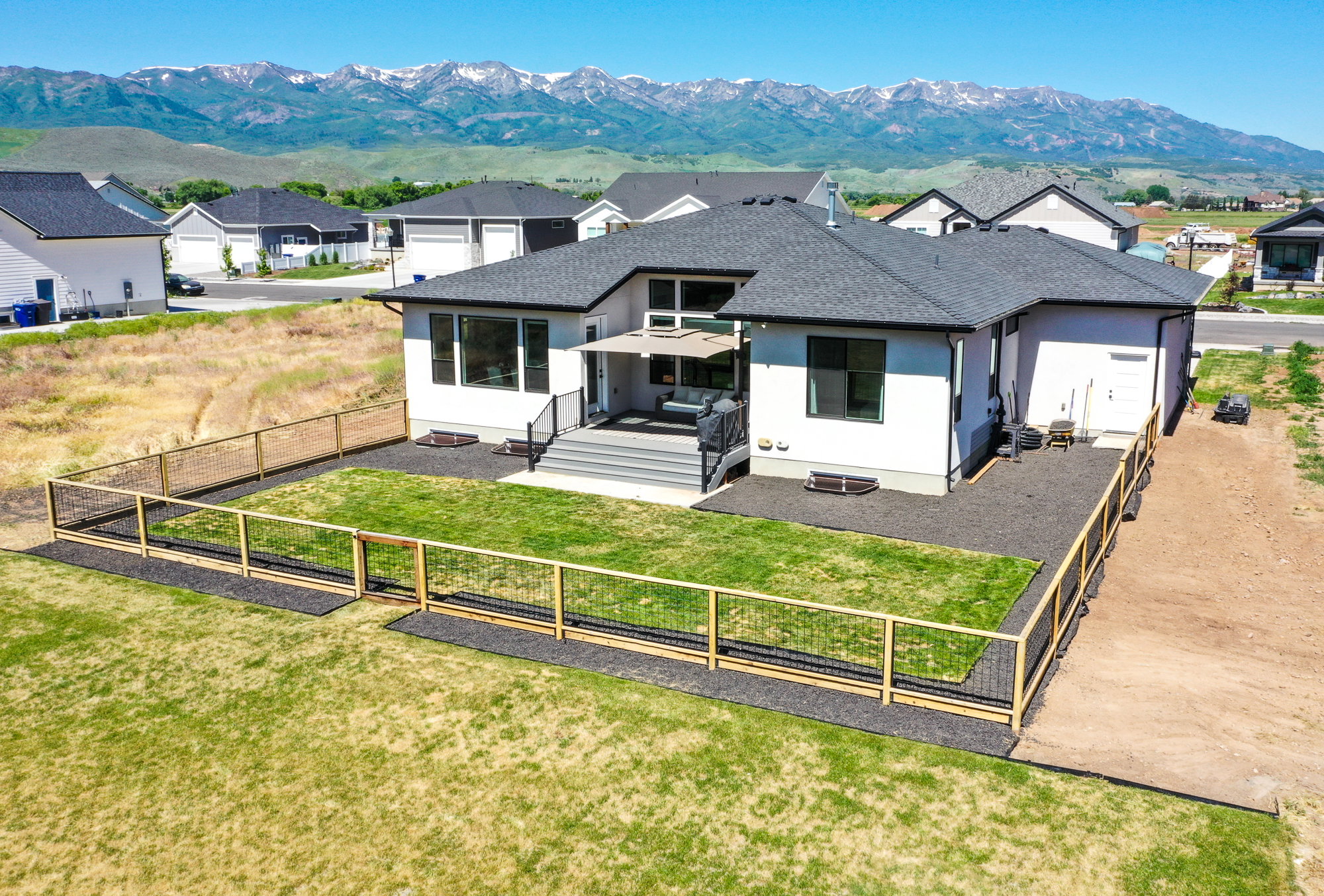 View of front facade with a mountain view, a residential view, stucco siding, a shingled roof, and a fenced backyard