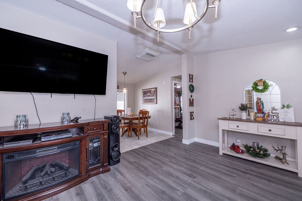 Living room featuring a chandelier, lofted ceiling, and dark wood-style floors