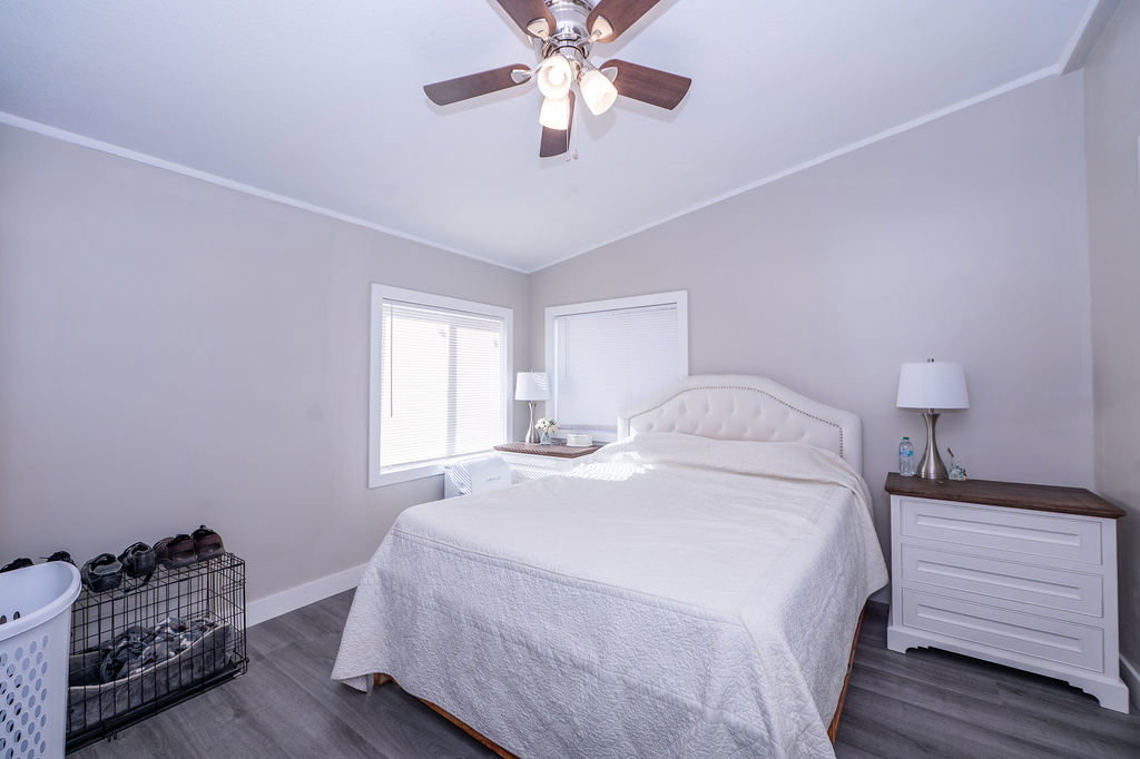 Bedroom with lofted ceiling, dark wood finished floors, a ceiling fan, and crown molding