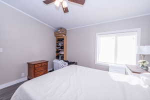 Bedroom with a ceiling fan, crown molding, and dark wood-style floors