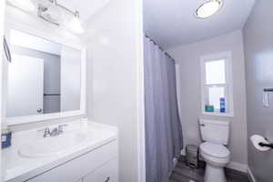 Bathroom with curtained shower, vanity, and dark wood-type flooring