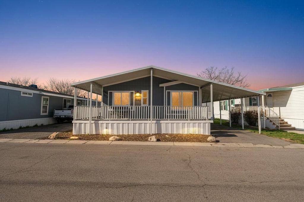 Manufactured / mobile home featuring a porch, a carport, and driveway