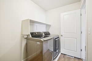 Laundry area with washing machine and clothes dryer and light wood-type flooring