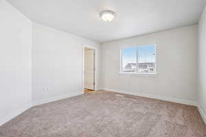 Spare room with baseboards and light colored carpet