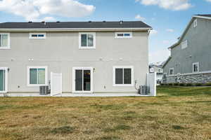 Rear view of house with a lawn, stucco siding, and a patio area