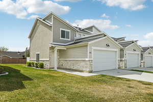 View of front of house featuring stone siding, an attached garage, and concrete driveway