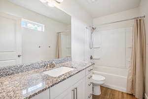Full bathroom with vanity, shower / tub combo, and dark wood-style flooring