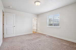 Unfurnished bedroom with baseboards and light colored carpet