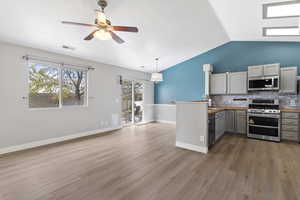 Kitchen with gray cabinetry, stainless steel appliances, hanging light fixtures, butcher block countertops, and lofted ceiling