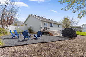 Rear view of house with a wooden deck, a fire pit, a patio area, and a fenced backyard