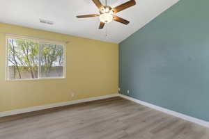 Empty room featuring light wood-type flooring, a ceiling fan, and vaulted ceiling