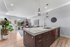 Kitchen with a peninsula, dark wood finish cabinets, light wood-style flooring, and light stone countertops