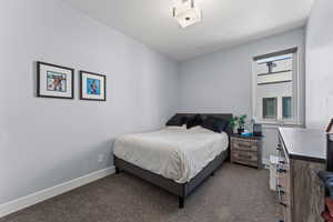 Bedroom with dark carpet and baseboards