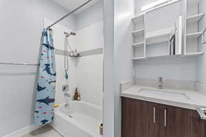 Bathroom featuring vanity, shower / bath combo, and light tile patterned flooring