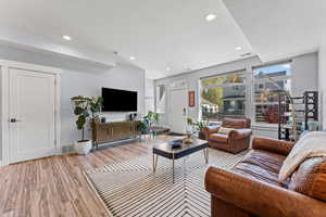 Living room with light wood-type flooring and recessed lighting