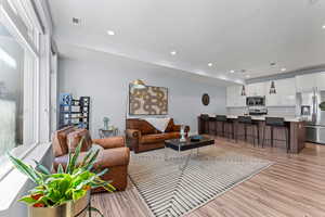 Living room with light wood-style flooring and recessed lighting