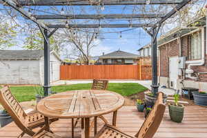 Wooden deck featuring outdoor dining area, a shed, a fenced backyard, and a patio area